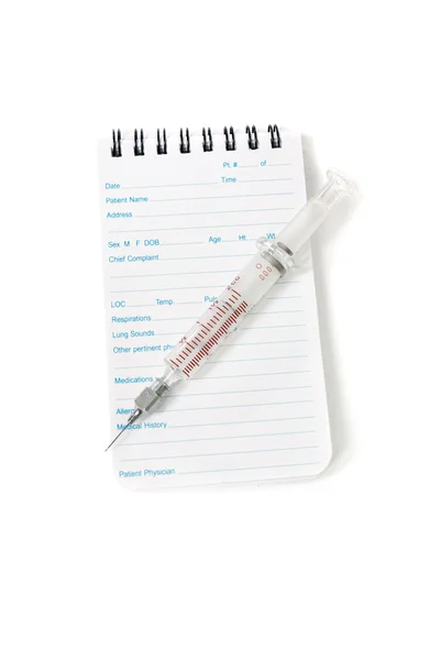 Notebook médico e agulha de seringa — Fotografia de Stock