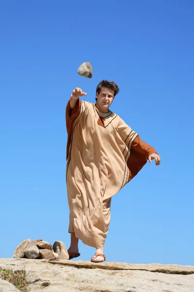 Древний человек бросает камень — стоковое фото
