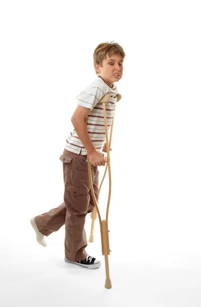 Wincing τραυματίες αγόρι χρησιμοποιώντας δεκανίκια — Φωτογραφία Αρχείου