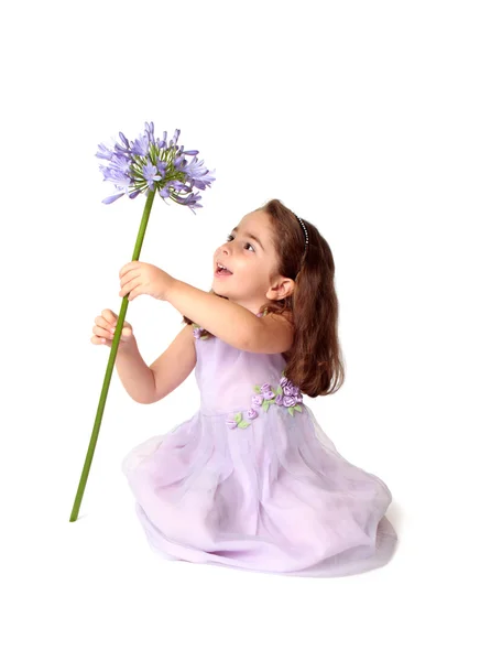 Klein meisje draaiingen grote paarse bloem — Stockfoto