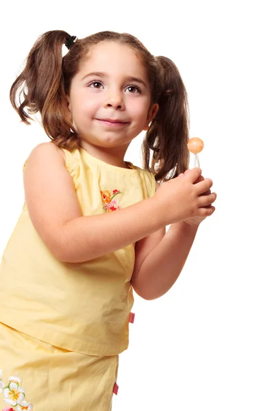 Маленькая девочка в хвостиках держит леденец — стоковое фото