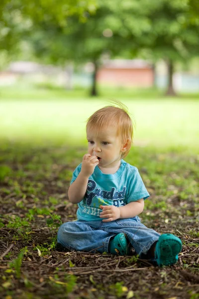 Cute little boy sitting on the ground — Stock Photo, Image