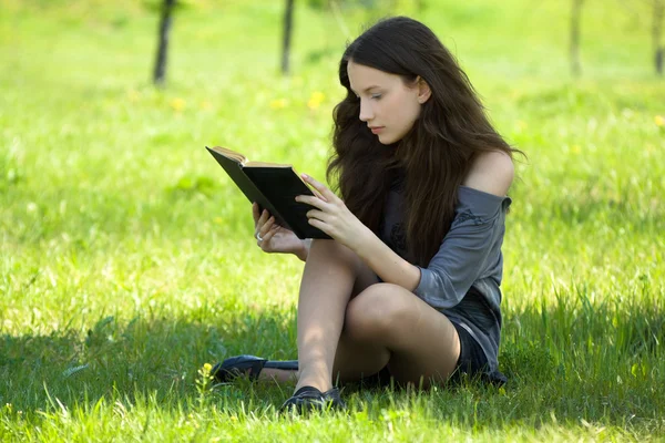 Jovem estudante ler livro no prado — Fotografia de Stock