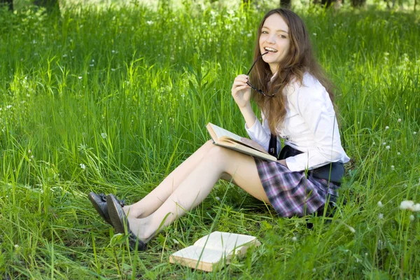 Mladá školačka v parku číst knihu — Stock fotografie