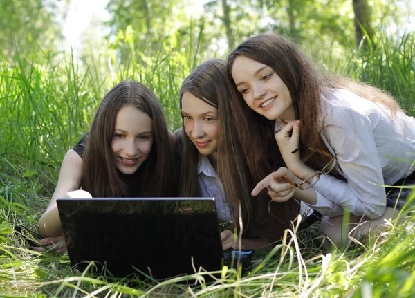 Três estudantes relaxar e rir sobre a grama do parque — Fotografia de Stock