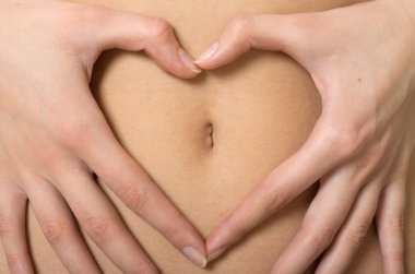 A woman's hands forming a heart symbol around navel clipart