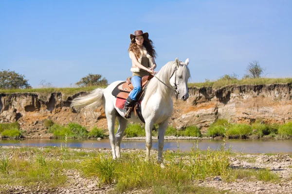 Mladí cowgirl na bílém koni v řece — Stock fotografie