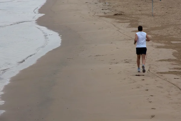Чоловік біжить на пляжі Стокове Фото