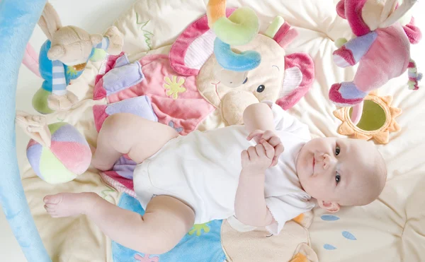 Bebê menina deitada no tapete de jogo — Fotografia de Stock