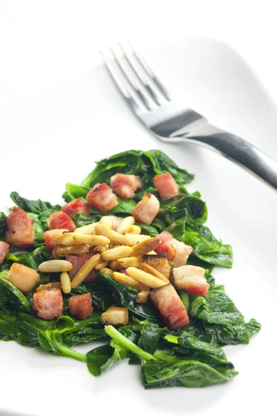 Fried spinach with bacon and pine nuts — Stock Photo, Image