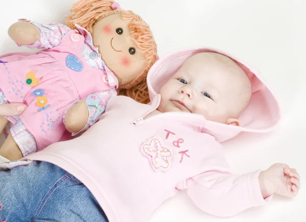 Babymeisje met een pop liggen — Stockfoto