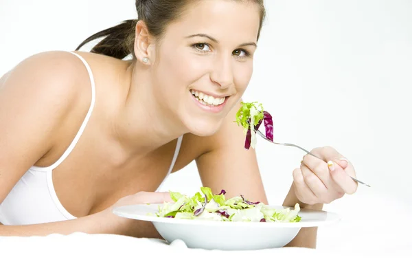 Retrato de una mujer acostada comiendo ensalada — Foto de Stock