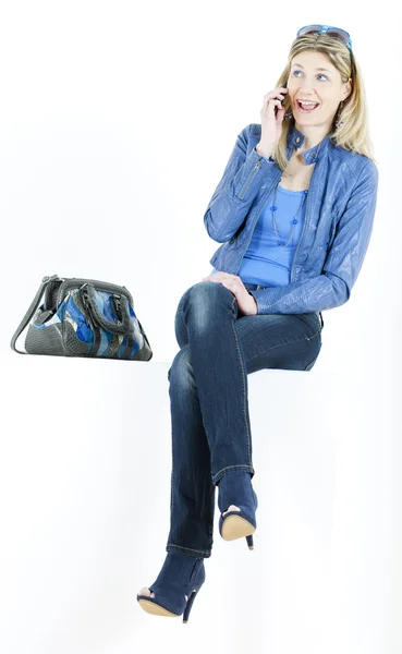 Mujer sentada con teléfono móvil y bolso — Foto de Stock