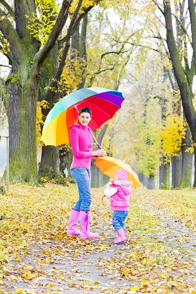 Μητέρα και κόρη με ομπρέλες σε φθινοπωρινό δρομάκι — Φωτογραφία Αρχείου