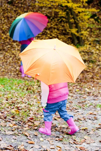 Mor och hennes dotter med paraplyer i höstliga naturen — Stockfoto