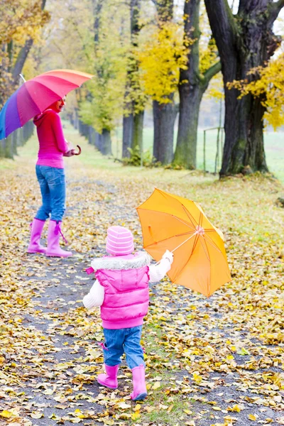 Мать и ее дочь с зонтиками в осеннем переулке — стоковое фото