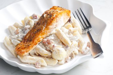 Baked salmon on pepper with creamy pasta clipart