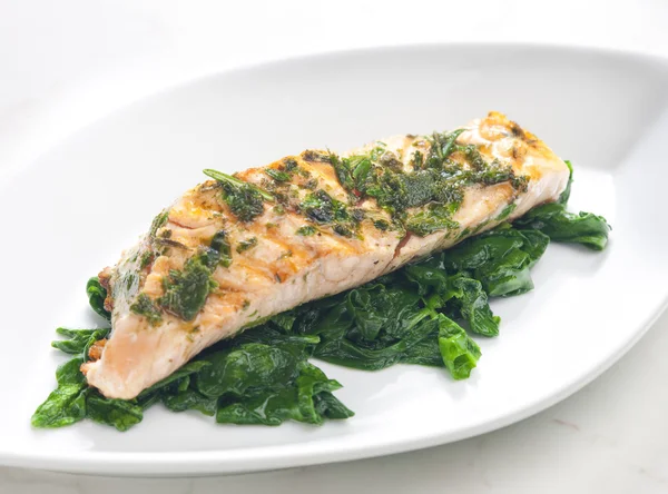 Grilled salmon with herbs on fried spinach — Stock Photo, Image