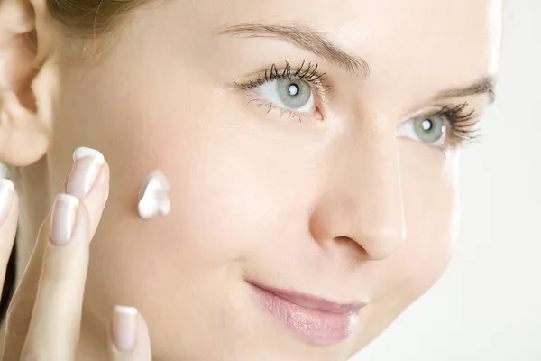 Donna che mette la crema su faccia — Foto Stock