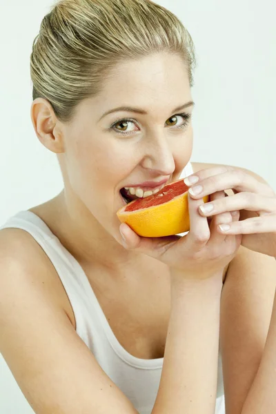 Portret van een jonge vrouw eten grapefruit — Stockfoto