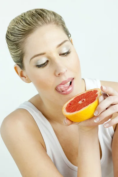 Portret van een jonge vrouw eten grapefruit — Stockfoto