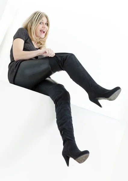 Sittande kvinna som bär trendiga svarta stövlar — Stockfoto
