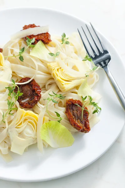 Pasta with dried tomatoes and artichokes — Stock Photo, Image