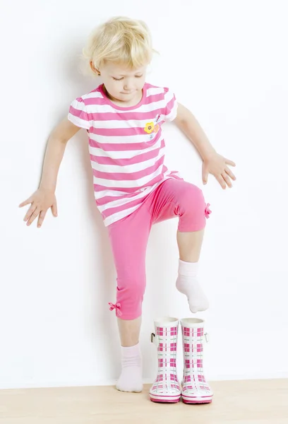 Klein meisje rubberen laarzen te zetten — Stockfoto