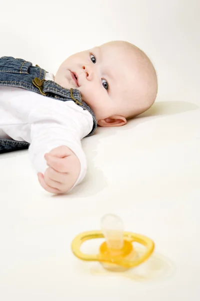 Bir emzik ile kız bebek aşağı yalan portresi — Stok fotoğraf