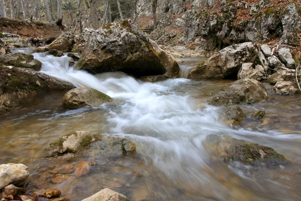 Snelle run van berg rivier onder stenen — Stockfoto