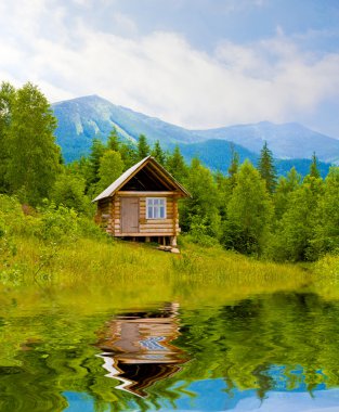 Wooden house in mountains near lake clipart