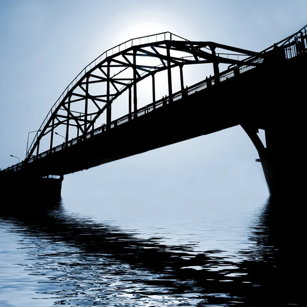 Dark bridge over river Stock Photo
