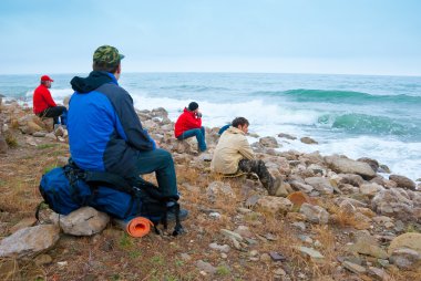 Hikers on a stony sea shore clipart