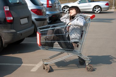 Pretty girl relaxes in a shopping cart clipart