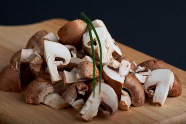 Heap of chopped mushrooms on a wooden board clipart