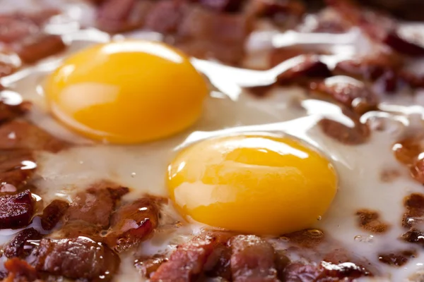 Närbild av två ägg och bacon i en stekpanna — Stockfoto