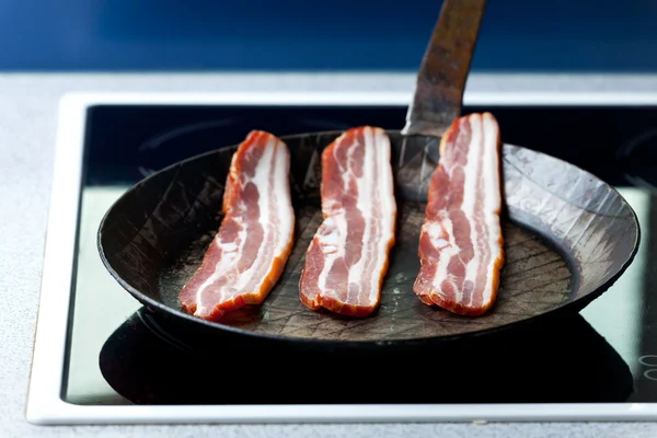 Três riscas de bacon em uma panela — Fotografia de Stock
