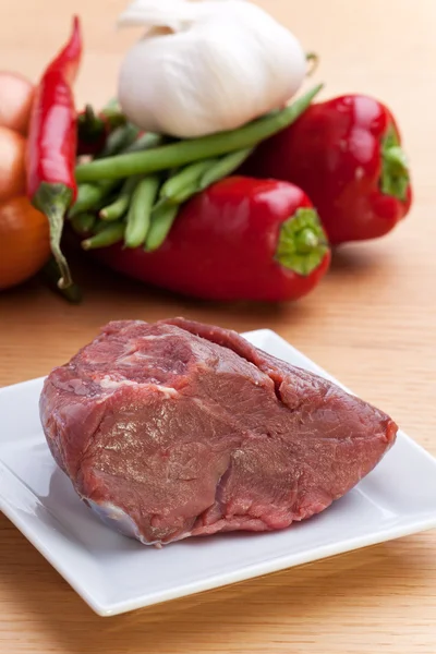 Surowe mięso i boczek paski na drewnianym stołem — Zdjęcie stockowe