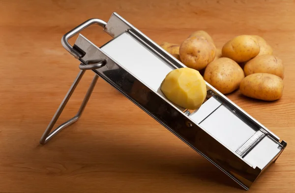 Hälften en potatis på en mandolin slicer — Stockfoto
