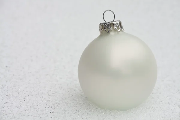 stock image White christmas bauble on the frozen ground
