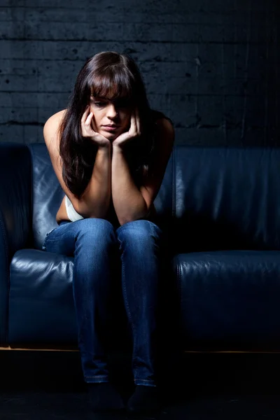 Kvinna på en läder soffa i förtvivlan — Stockfoto