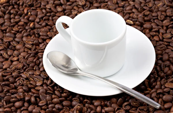 Copo de café branco sentou-se em grãos de café — Fotografia de Stock