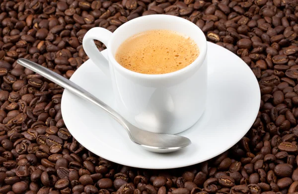 Bílá espresso šálek plný kávy seděl na kávová zrna — Stock fotografie
