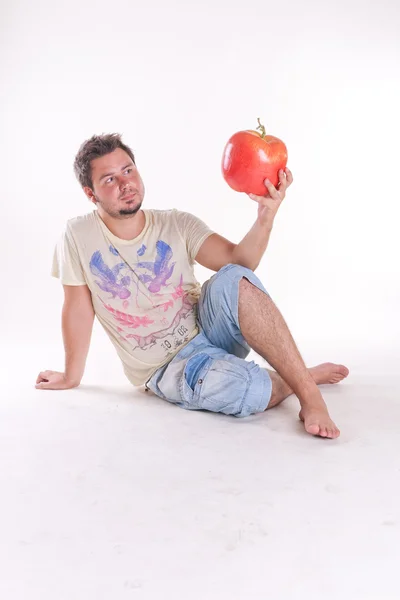 Stock image Young man bites a huge tasty apple, on white