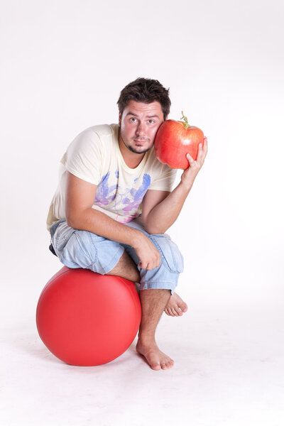Young man bites a huge tasty apple, on white