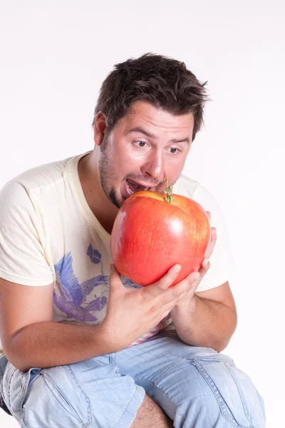 Jonge man bijt een enorme lekkere appel op wit — Stockfoto