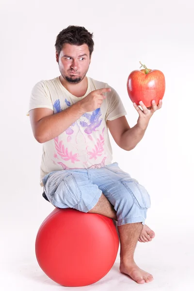 Молодий чоловік кусає величезне смачне яблуко, на білому — стокове фото
