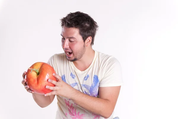 Jovem morde uma enorme maçã saborosa, em branco — Fotografia de Stock