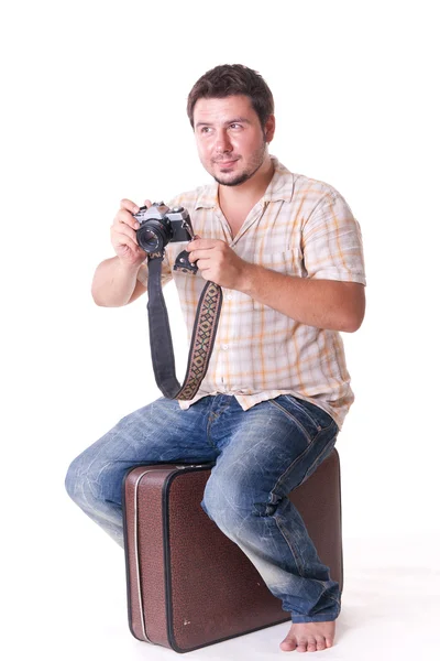 Young man with old-fashion 35mm camera sitting on suitcase, on white — Stock Photo, Image