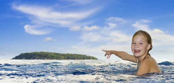 Девушка в море указывает на остров — стоковое фото